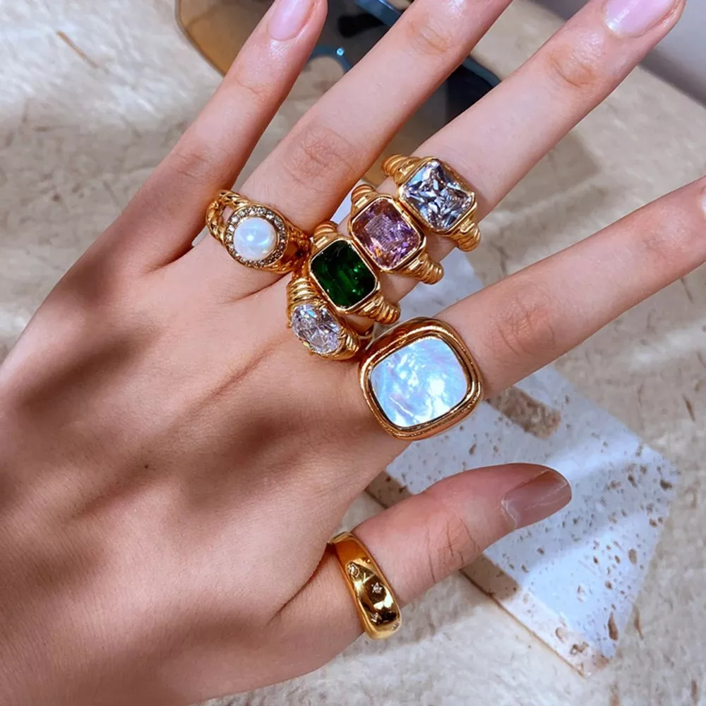 Hand wearing multiple colorful gemstone rings