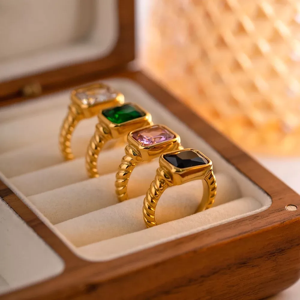 Gold rings with colorful gemstones in a box.