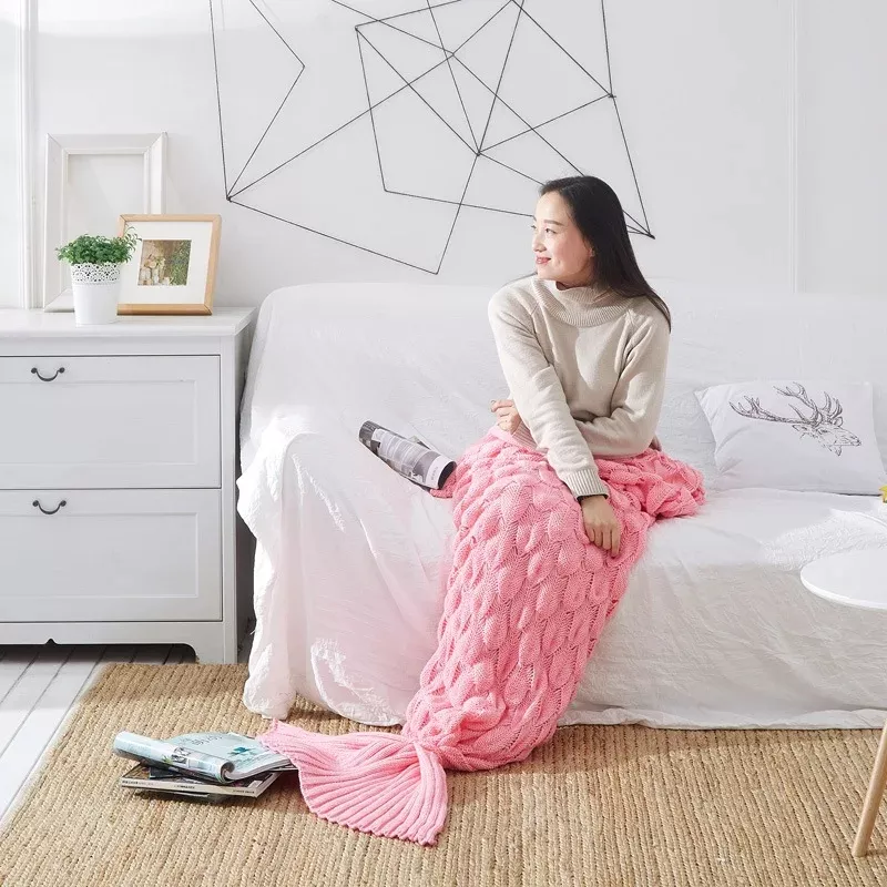 Woman with pink mermaid tail blanket on sofa