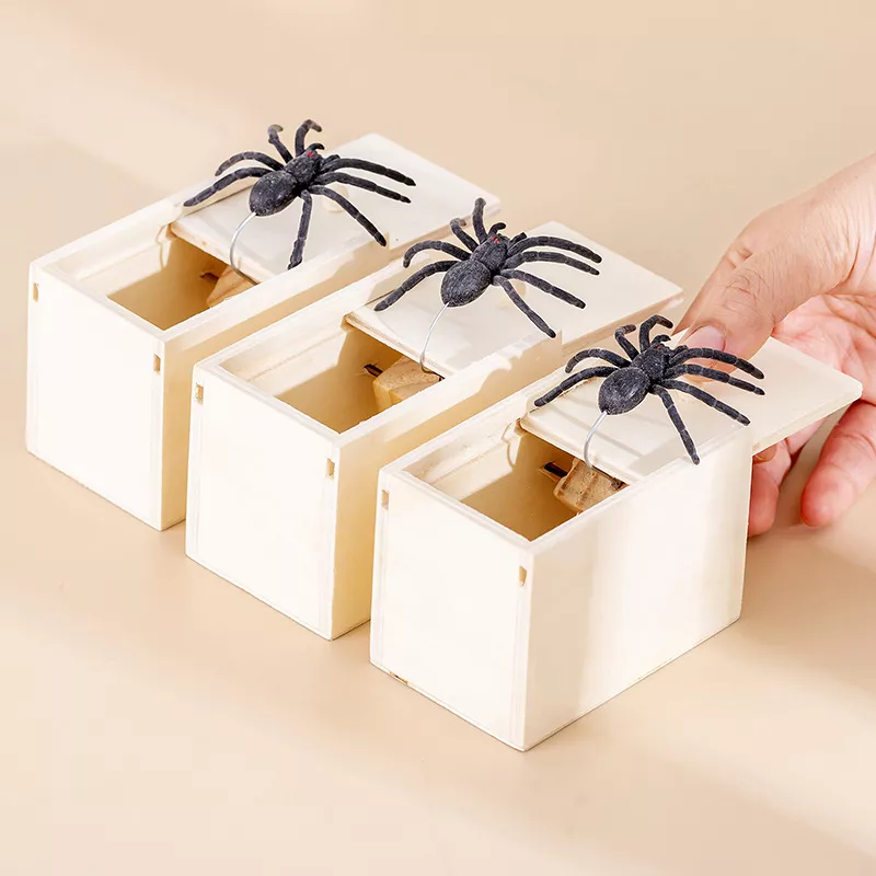 Three wooden boxes with fake spiders on lids.