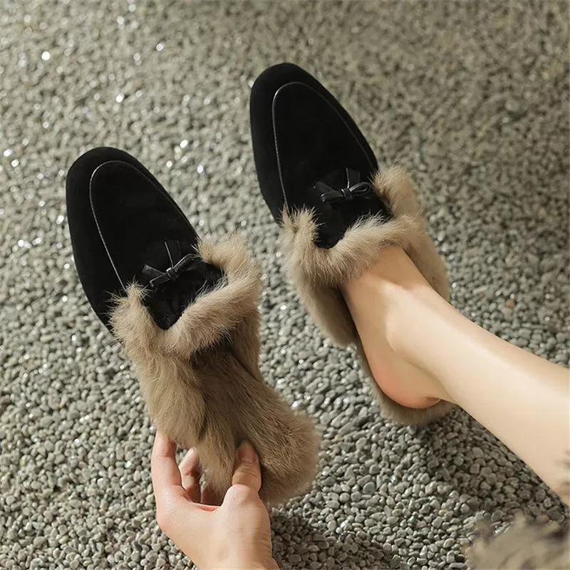 Woman wearing fur-lined black loafers on pebbles